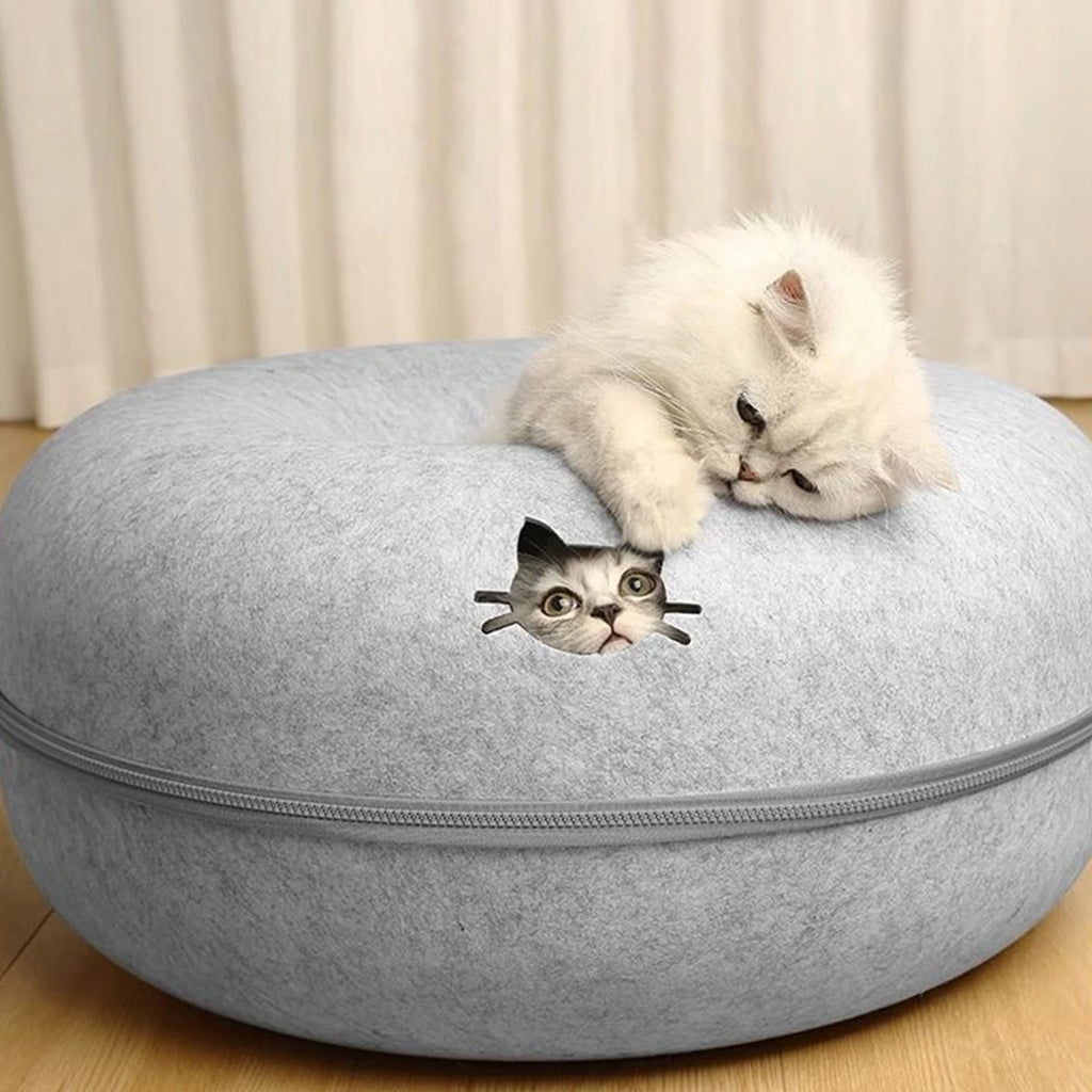 Cat peeking out of a light grey felt donut cat bed